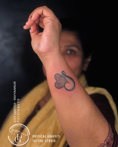 a woman with a tattoo on her arm holding up the letter s in front of her face