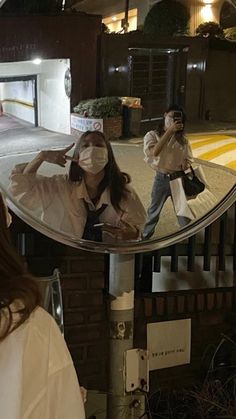 a woman wearing a face mask is taking a selfie in front of a mirror