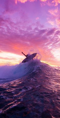 a person riding a surfboard on top of a wave in the ocean at sunset