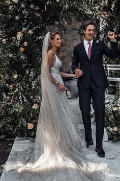 a bride and groom standing in front of an arch with roses on it at their wedding