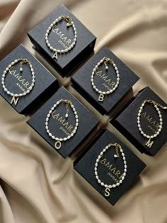 four black boxes with pearls on them sitting on a bed