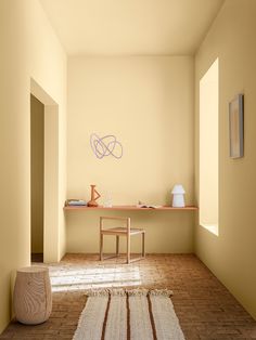 an empty room with yellow walls and a white rug on the floor next to a wooden table