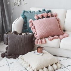 a white couch with some pillows and a coffee cup on the floor next to it