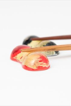 two chopsticks and an apple on a white surface