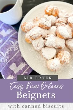 a plate with powdered sugar covered pastries on it next to a cup of coffee