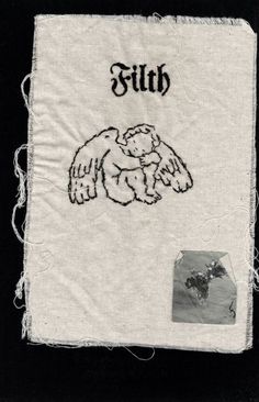 an embroidered cloth with the word faith written in black ink on it and angel wings