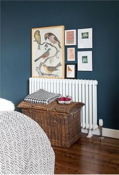 a bedroom with blue walls and pictures on the wall above the radiator, along with a wicker basket