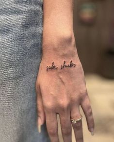 a woman's hand with a small tattoo on it that says, soler shaker