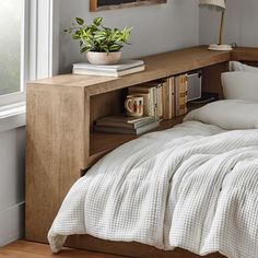 a bed with white sheets and pillows next to a book shelf filled with books on top of it