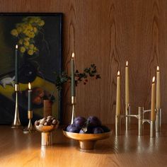 a wooden table topped with candles next to a bowl filled with fruit and veggies