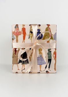 a gift wrapped in wrapping paper with women's clothing on it and a bow