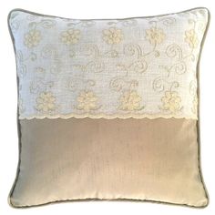 a white and beige pillow with flowers on the front, along with an embroidered border