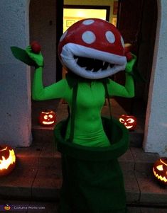 a woman dressed as a mushroom standing in front of pumpkins