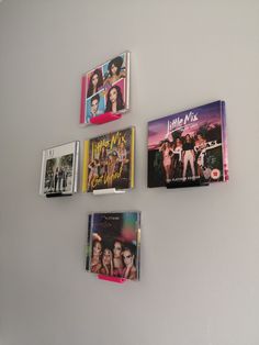 four cd's are hanging on the wall in front of each other, including one for little mix