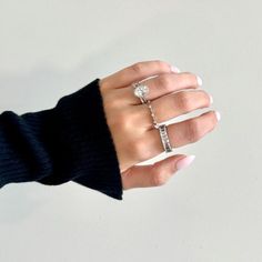 a woman's hand with three different rings on her fingers and one is wearing a black sweater