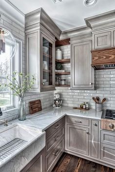 a kitchen with white marble counter tops and wooden cabinetry, along with a window