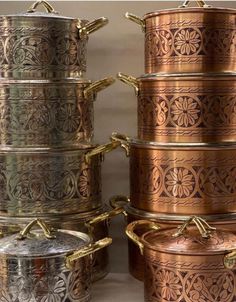 several pots and pans are stacked on top of each other, with gold handles