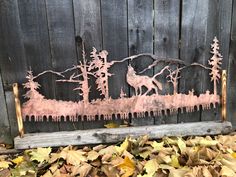 a metal horse on a wooden fence surrounded by leaves and fallen leaves in front of it