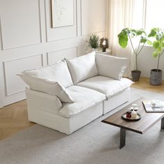 a living room with a couch and coffee table in front of a large white wall