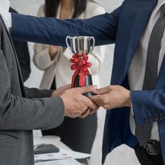 two people exchanging money with a trophy on their hands at a business meeting in the office