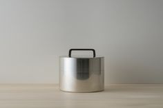 a large metal container sitting on top of a wooden table next to a white wall