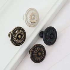 three door knobs on top of a white surface next to each other and one has an ornate design in the middle