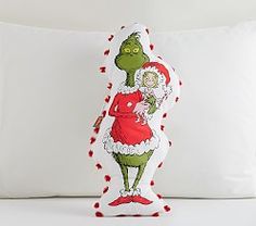 the grinch pillow is on display in front of a white pillow with red trim