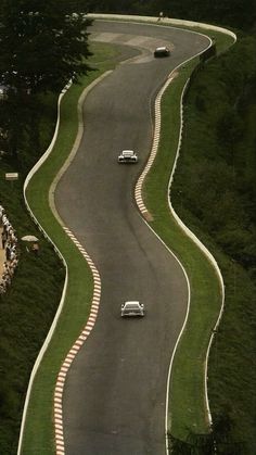 two cars are driving down the winding road