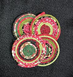 four circular pieces of fabric sitting on top of a black table cloth covered in green, red and white circles