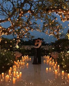 a man and woman embracing in front of many lit candles