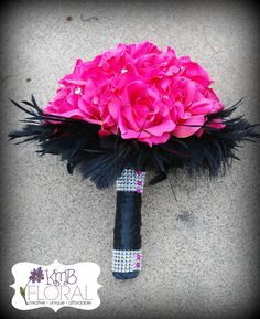 a bouquet of pink flowers and feathers is on the ground next to a black umbrella