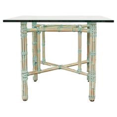 a table with glass top and green bamboo trimmings on the base, against a white background