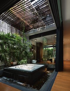 an indoor jacuzzi tub in the middle of a wood floored room with plants