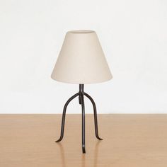 a lamp sitting on top of a wooden table next to a white wall and floor