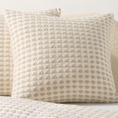 three pillows on top of each other with white and beige dots in the middle one is made out of linen