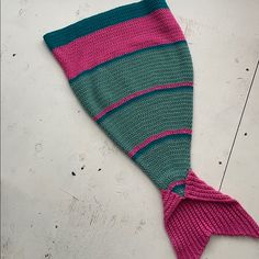 a knitted mermaid tail laying on top of a white floor with pink and green stripes