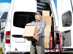 a man holding two boxes in front of a van