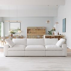 a white couch sitting in the middle of a living room next to a wooden table