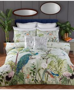 an image of a bedroom setting with peacocks on the comforter and tropical plants