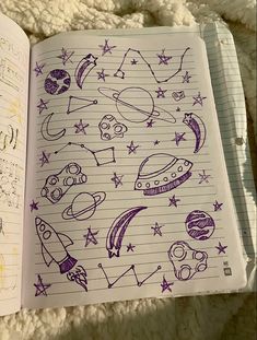 an open notebook with doodles and space related drawings on the pages in purple ink