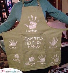 a woman wearing an apron with handprints on it and the words grandma's helping hands