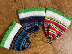 two knitted mittens sitting on top of a wooden floor next to each other