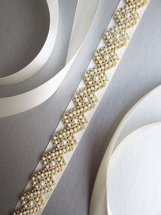 This elegant bridal belt features beautiful criss-cross pearl and crystal design. The crystal beading measures 7/8 wide and 27 long. The entire sash measures 150. Available in gold, silver or rose gold finish and with satin or organza ribbon. Shown in the photos in gold finish with Elegant Embellished Bridal Belt For Mother Of The Bride, Elegant Gold Bridal Belt For Bridesmaids, Elegant Rhinestone Bridal Belt For Bridesmaids, Elegant Pearl Embellished Sashes For Party, Elegant Gold Bridal Accessories With Sashes, Elegant Beaded Bridal Belt For Party, Elegant Bridal Accessories With Pearl Embroidery, Elegant Gold Bridal Belt For Bride, Elegant Gold Belts With Rhinestones