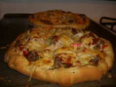 two pizzas sitting on top of a pan covered in cheese and meat toppings