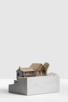 an architectural model of a house on top of a block of concrete with trees growing out of it