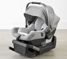 an infant car seat sitting on top of a hard wood floor next to a white wall