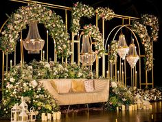 a couch sitting in front of a bunch of flowers and chandeliers on a stage