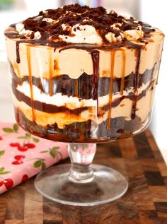 an ice cream sundae with chocolate sauce and whipped cream on top, sitting on a wooden table