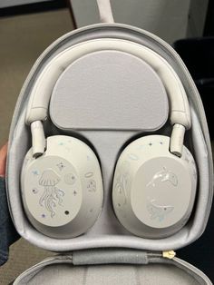 a pair of white headphones sitting inside of a gray case on top of a chair