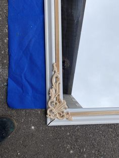 a mirror sitting on the ground next to a blue tarp and a pair of shoes